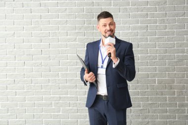 Tuğla arka planda mikrofonu olan erkek gazeteci