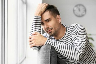 Depresyondaki genç adam evinin penceresinin yanında.