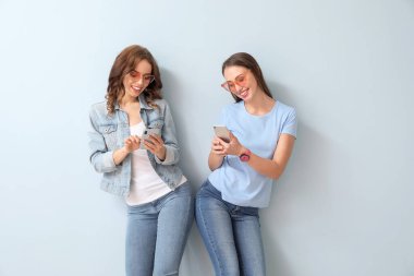 Renkli arka planda cep telefonu olan genç kadınlar