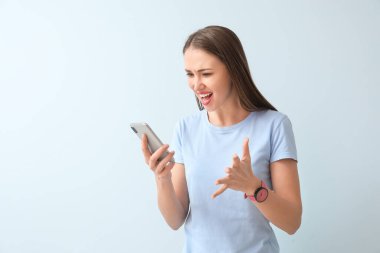 Arka planda cep telefonu olan öfkeli genç bir kadın.