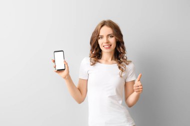 Cep telefonlu genç bir kadın arka planda başparmak kaldırıyor