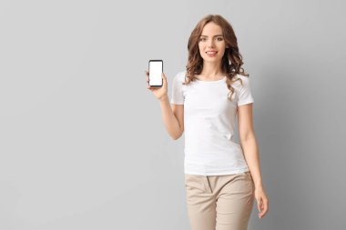 Arka planda cep telefonu olan genç bir kadın.