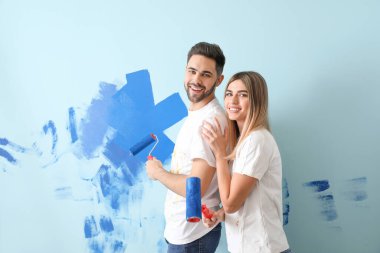 Mutlu genç çift yeni evlerinde duvar boyuyor.