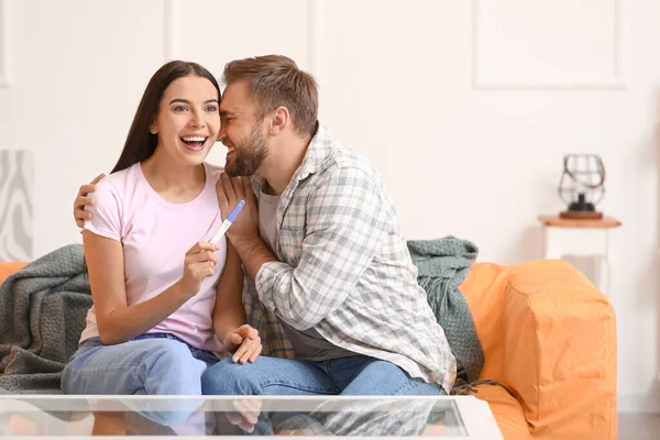 Happy young couple with pregnancy test at home