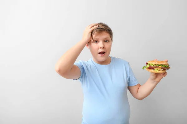 Übergewichtiger Junge Mit Burger Auf Hellem Hintergrund — Stockfoto