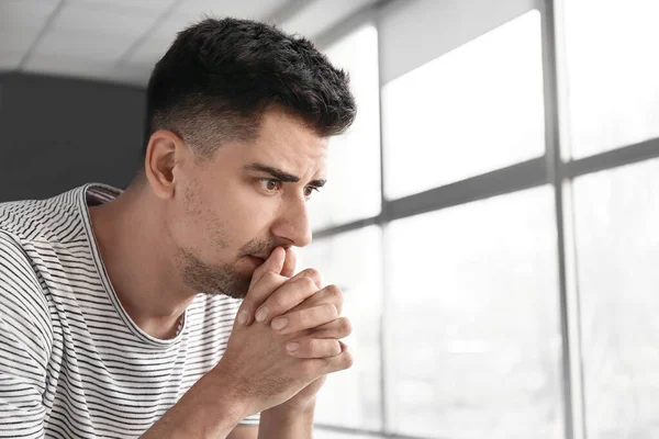 Depressed young man near window