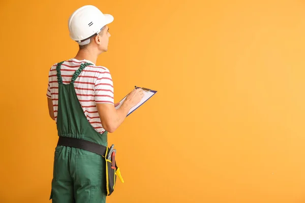 Handsome male worker with clipboard on color background