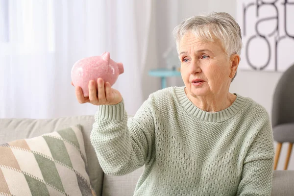 Senior woman with piggy bank at home