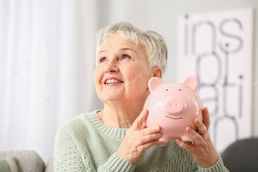 Senior woman with piggy bank at home
