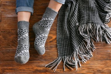 Örgü çoraplı kadın bacakları ve ahşap arka planda ekose.