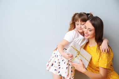 Küçük kızı gri arka planda annesini selamlıyor.