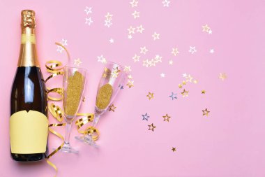 Bir şişe lezzetli şampanya ve renkli dekorlu bardaklar.