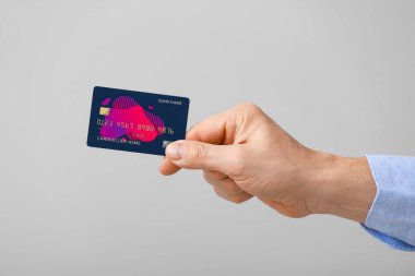 Gri arka planda kredi kartı olan bir erkek.