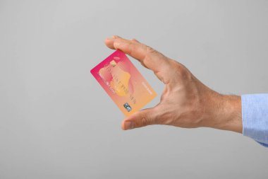 Gri arka planda kredi kartı olan bir erkek.