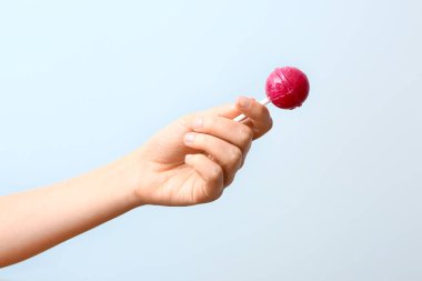 Hafif arka planda tatlı lolipopu olan kadın eli
