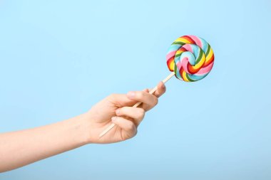 Renkli arka planda tatlı lolipopu olan kadın eli