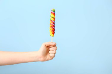 Renkli arka planda tatlı lolipopu olan kadın eli