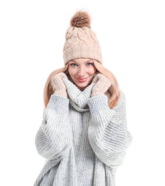 Beyaz arka planda kalın kazaklı, şapkalı ve eldivenli genç bir kadın.