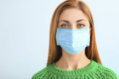Arka planda koruyucu maskesi olan genç bir kadın. Salgın kavramı