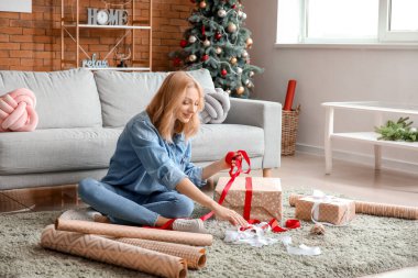 Güzel genç bir kadın Noel hediyelerini paketliyor.