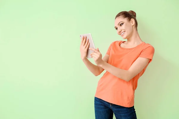 Young woman with tablet computer on color background