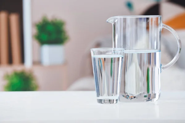 部屋のテーブルの上に新鮮な冷たい水のガラスとジャグ — ストック写真