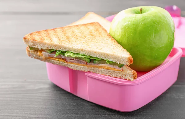 School lunch box with tasty food on wooden background