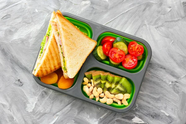 School lunch box with tasty food on grey background