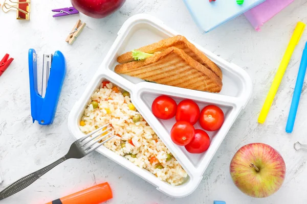 おいしい食べ物とテーブルの上に文房具を備えた学校の弁当箱 — ストック写真