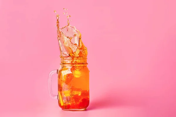 冷たいお茶のメイソンジャーの色の背景にスプラッシュ — ストック写真