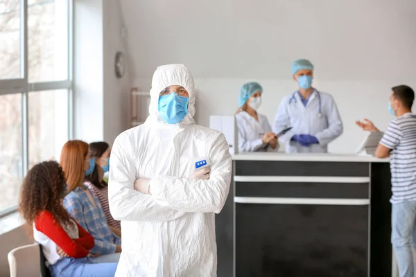 Doctor in protective uniform and with thermometer in clinic