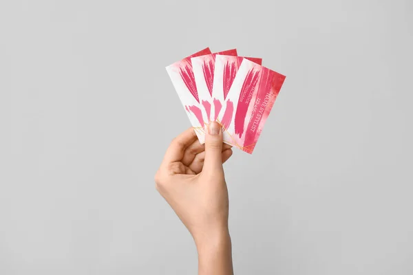 Female hand with business cards of makeup artist on grey background