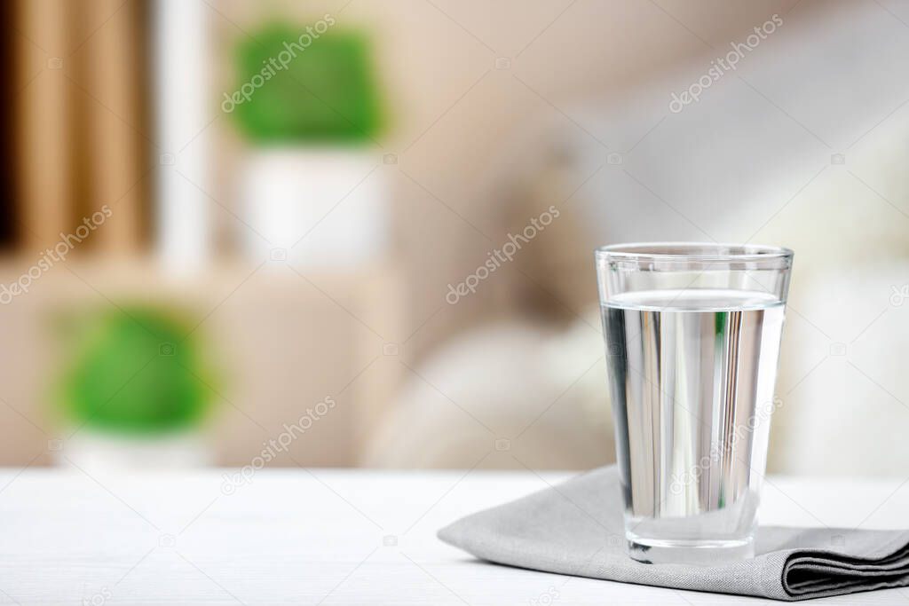 Glass of fresh cold water on table in room