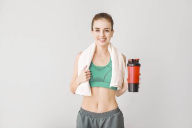 Hafif arka planda protein içeceği olan sportif genç bir kadın.