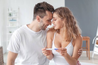 Banyoda hamilelik testi olan mutlu genç bir çift.