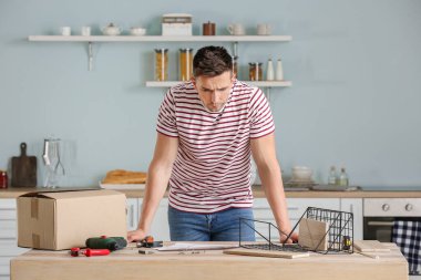 Genç adam evde mobilya montajı yapıyor.