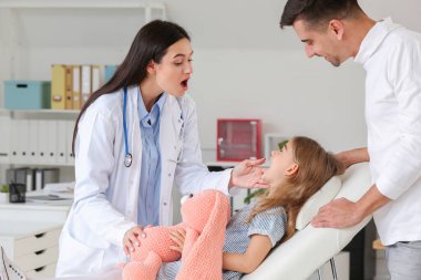 Küçük kızıyla birlikte çocuk doktorunu klinikte ziyaret eden bir adam.