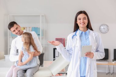 Küçük kızıyla birlikte çocuk doktorunu klinikte ziyaret eden bir adam.