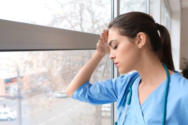 Depresyondaki kadın doktor kliniğin penceresinin yanında