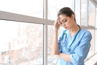 Depresyondaki kadın doktor kliniğin penceresinin yanında
