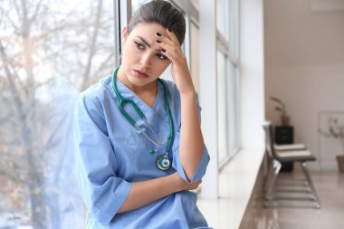 Depresyondaki kadın doktor kliniğin penceresinin yanında