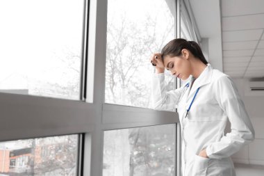 Depresyondaki kadın doktor kliniğin penceresinin yanında