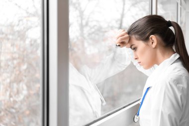 Depresyondaki kadın doktor kliniğin penceresinin yanında