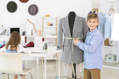 Atölyedeki mankenin yanında şirin bir terzi.