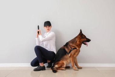 Female police officer with dog near light wall