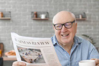 Evde gazete okurken çay içen yaşlı bir adamın portresi