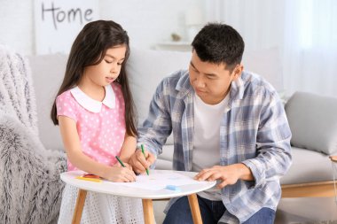 Asyalı bir adam ve küçük kızı evde resim çiziyorlar.