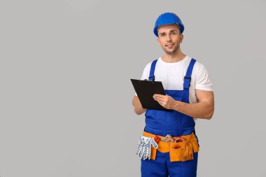 Gri arkaplanı olan yakışıklı bir erkek işçi.