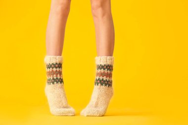 Arka planda sıcak örülmüş çoraplı genç bir kadının bacakları.