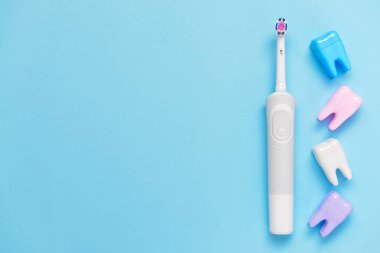 Elektrikli diş fırçası ve arka planda plastik diş.